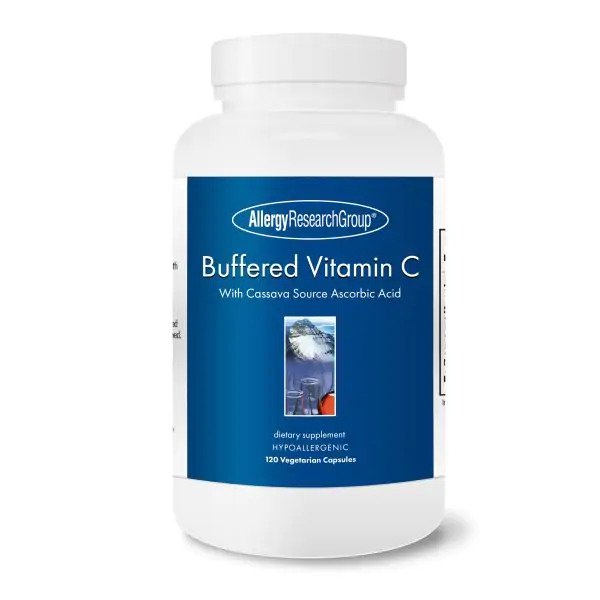 A close-up image of the Allergy Research Buffered Cassava Vitamin C capsules in a translucent container, highlighting their smooth, oval shape and light colour, with a blurred background of the product packaging and a mention of 120 capsules on the label