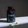 Close-up of the small, vegan-friendly tablet showing the complete B vitamin complex in a recyclable glass bottle with label details