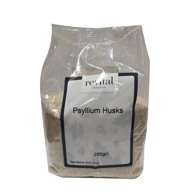 A close-up image of Revital Whole Foods Psyllium Husks in a clear glass jar, showing light tan, coarse husks used as a soluble fibre supplement to support digestion and promote healthy bowel movements