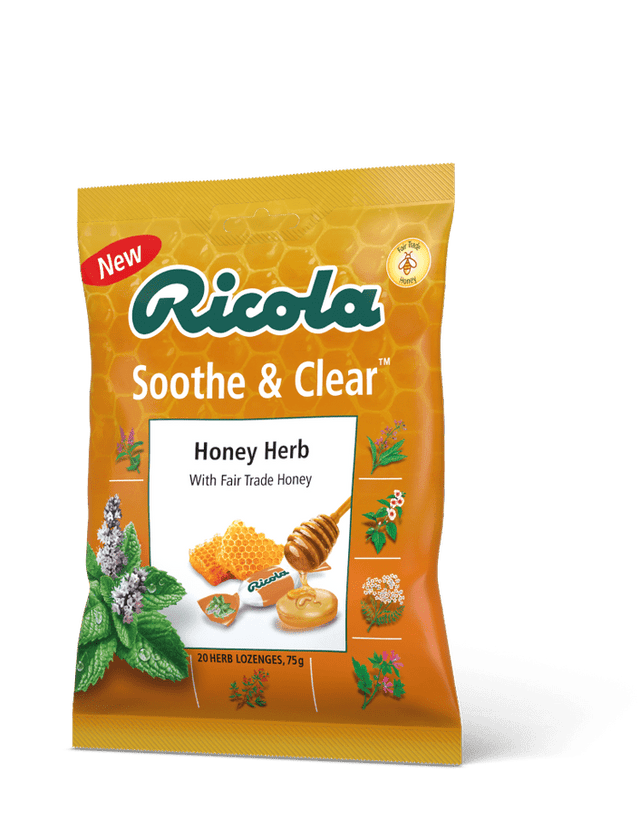 A close-up of Ricola Soothe & Clear Honey Herb lozenges in a transparent wrapper, showcasing their smooth, honey-coloured surface with subtle herbal specks, highlighting the natural ingredients and Swiss herbal blend used for soothing throat relief