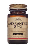 An image showing two Solgar Astaxanthin 5mg softgel capsules lying on a white surface, illustrating the product packaging and natural composition
