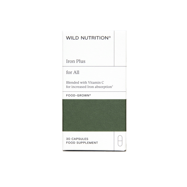 Close-up of Wild Nutrition Iron Plus capsules showing nutrient-rich ingredients like citrus pulp and yeast in a clean, bright setting