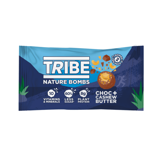 A close-up image of Tribe Nature Bomb Cashew 40g, showcasing two protein balls filled with creamy cashew butter, coated in rich dark chocolate with visible cacao nibs, surrounded by ingredients like sunflower seeds and oats